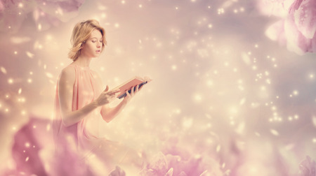 Young woman reading a book in pink peony fantasy environmentの写真素材