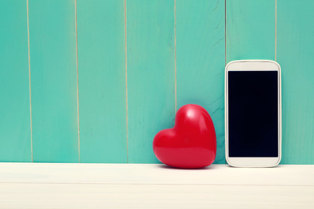 Love and technology theme with big red heart and smart phoneの写真素材
