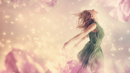 Beautiful woman in a green dress in a pink peony flower fantasyの写真素材