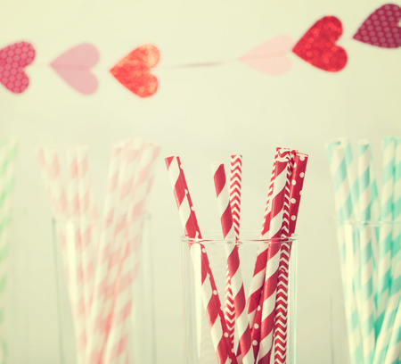 Colorful paper straws with a decorative garland of hearts symbolic of love to celebrate a party for a festive romantic occasionの写真素材