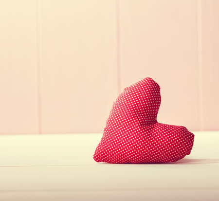 Red heart pillow on pink wooden wallの写真素材