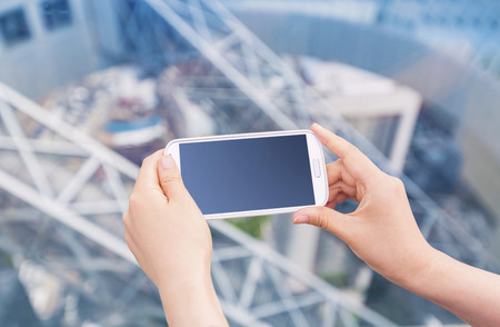 Person holding a smartphone on a blue metal industrial backgroundの写真素材