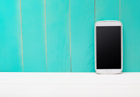 White smart phone on teal wooden backgroundの写真素材