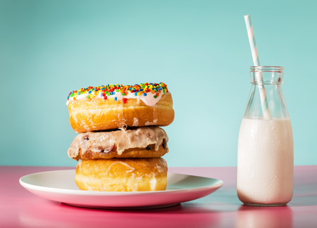 Stack of donuts with milk in a jar on pastel pink and blue backgroundの写真素材