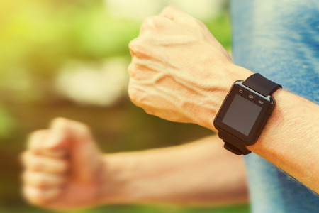 Male jogger running with a smartwatch outside in nature