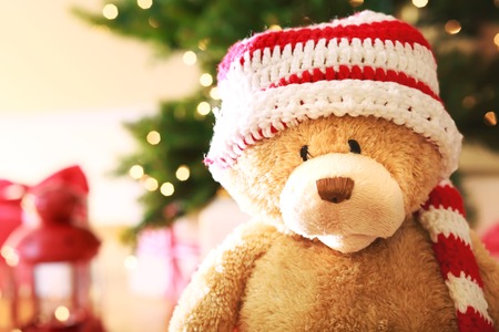 Bear wearing Santa hat with Christmas gift boxes on a white carpet at night