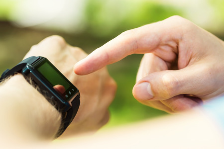 Mans hand pointing at his smartwatch outside