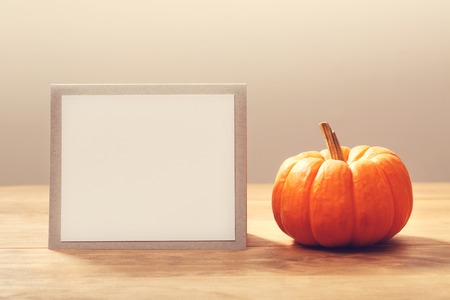 Autumn orange small pumpkin with message card on wooden tableの写真素材