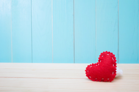 Hand crafted red felt heart on blue wood backgroundの写真素材