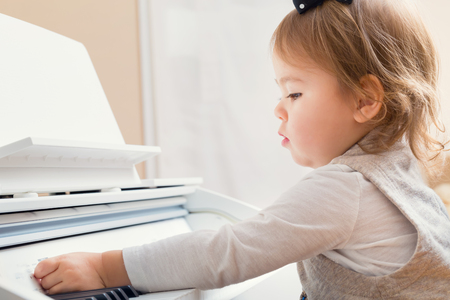 Little toddler girl playing piano in her houseの写真素材