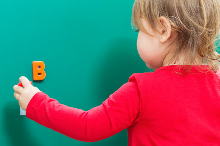 Toddler girl learning her alphabet letters on a chalkboardの写真素材