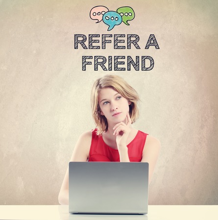 Refer A Friend concept with young woman working on a laptopの写真素材