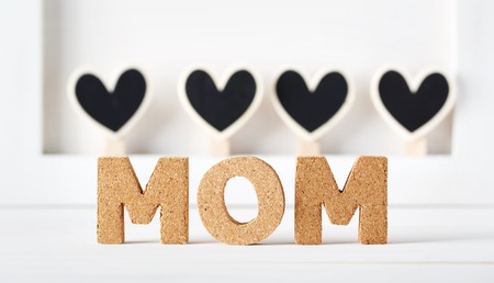 Cork Mom texts with black wooden hearts on a white tableの写真素材