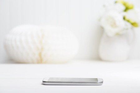Smartphone on the table with flower vaseの写真素材