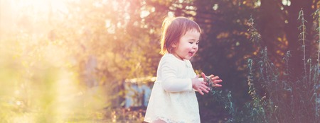 Happy toddler girl playing outside at sunsetの写真素材