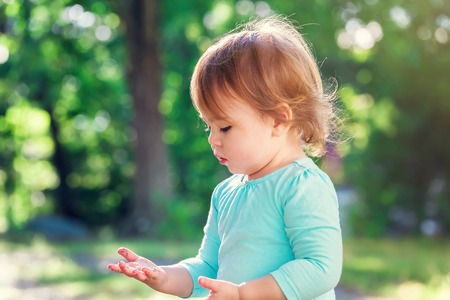 Happy toddler girl playing outside on a summer dayの写真素材