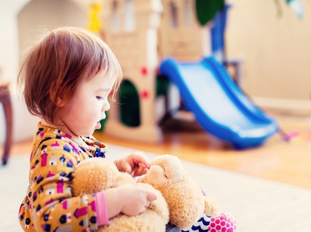 Toddler girl playing with her teddy bearの写真素材