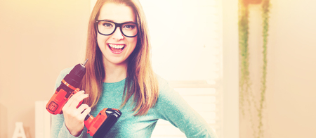 Young woman with cordless drill ready for home repairs