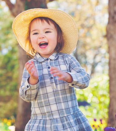 Happy toddler girl in a hat playing outsideの写真素材