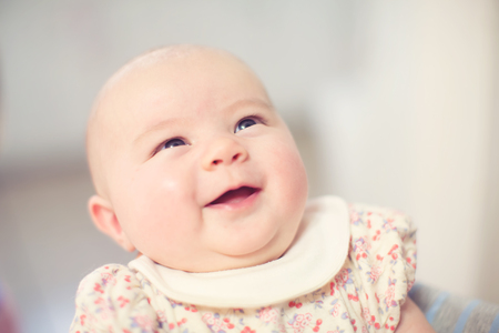 Newborn infant baby girl smiling in the arms of her motherの写真素材