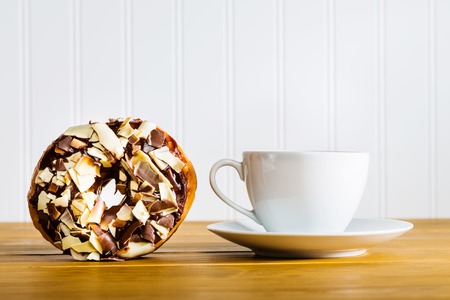 Chocolate donut with coffee mug on wooden tableの写真素材