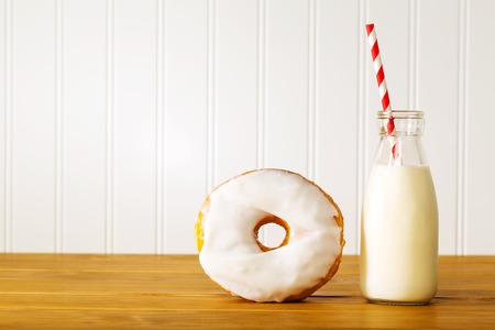 White glazed donut with jar of milk on wooden backgroundの写真素材