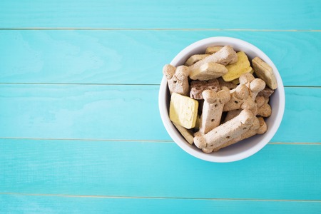 Dog treats in a bowl on wooden tableの写真素材