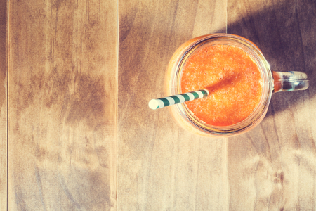 Mason jar with carrot juice smoothie and green strawの写真素材