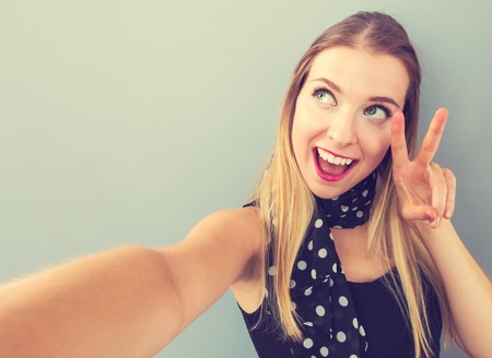 Young woman taking a selfie on a gray backgroundの写真素材