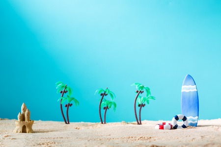 Summer theme with surfboard and sand castle on a bright blue backgroundの写真素材