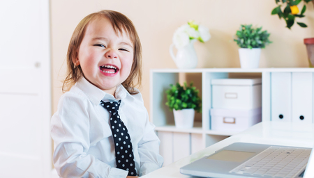 Happy toddler girl laughing while using her laptopの写真素材