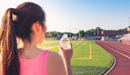 Female athlete drinking water on at a stadium running trackの写真素材