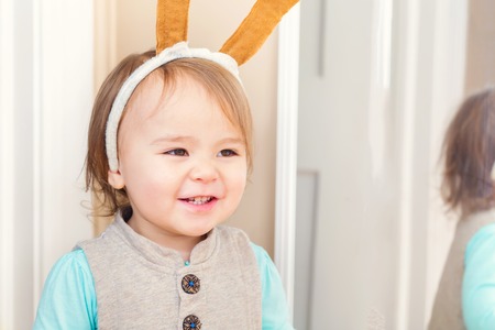 Happy toddler girl playing with costume ears in her houseの写真素材