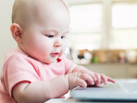 Happy baby girl using a laptop computerの写真素材