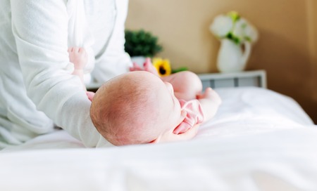 Newborn baby girl lying being cared for by her motherの写真素材