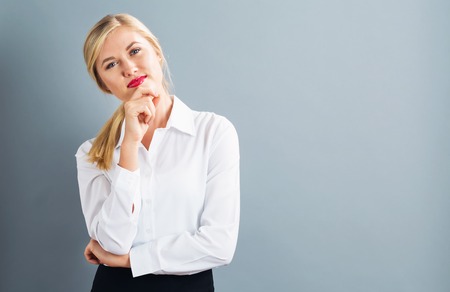 Young businesswoman in a thoughtful pose on a gray backgroundの写真素材