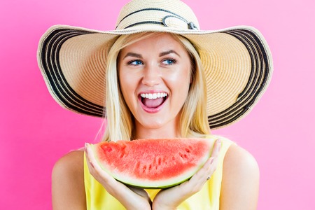 Happy young woman holding watermelon on a pink backgroundの写真素材