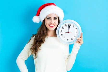 Young woman holding a clock showing nearly 12の写真素材