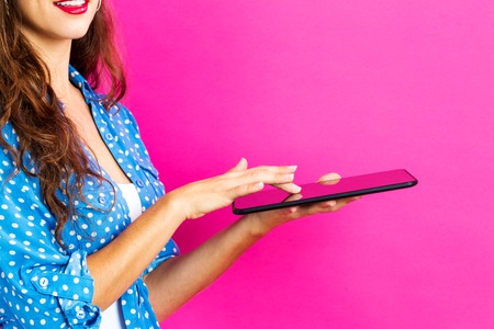 Young woman using her table on a pink backgroundの写真素材