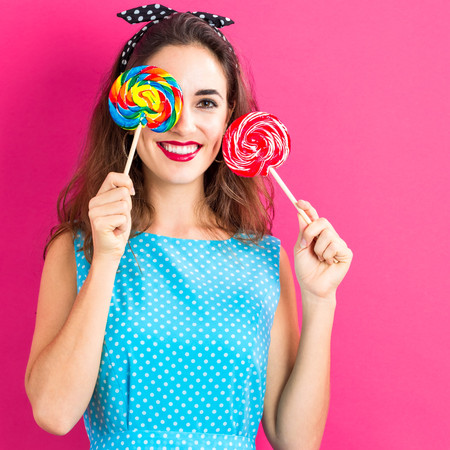 Young woman holding lollipops on a pink backgroundの写真素材