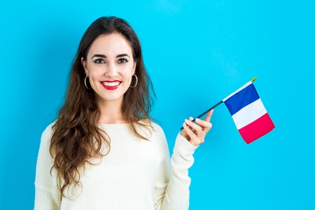 Happy young woman holding French flag on a blue backgroundの写真素材