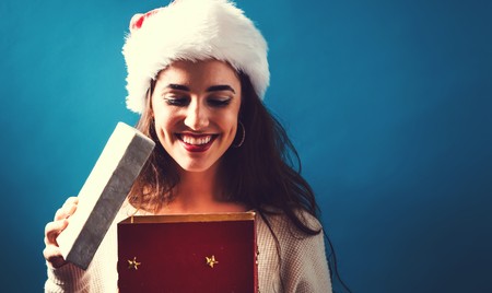 Happy young woman opening a Christmas present boxの写真素材