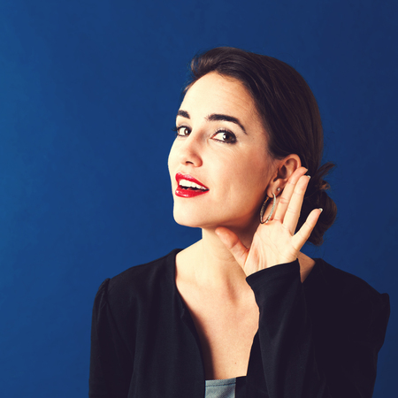 Young woman listening on a blue backgroundの写真素材