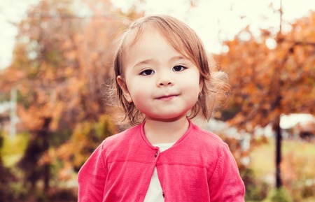 Happy toddler girl smiling outside in autumn