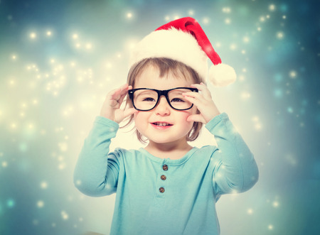 Happy toddler girl with Santa hat wearing glassesの写真素材
