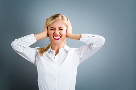Young woman blocking her ears on a gray backgroundの写真素材