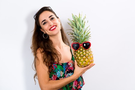 Happy young woman holding a pineapple on a white backgroundの写真素材