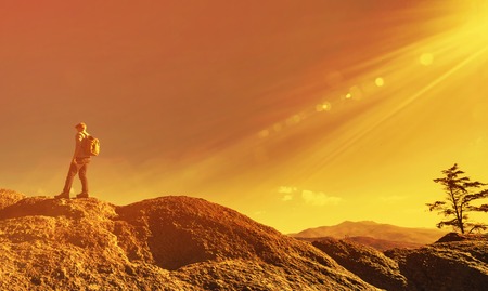 Man walking on the edge of a cliff high above the mountainsの写真素材