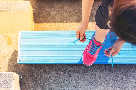 Female runner lacing her sneakers on in the bleachers of a stadium