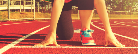 Female athlete on the starting line of a stadium track preparing for a runの写真素材